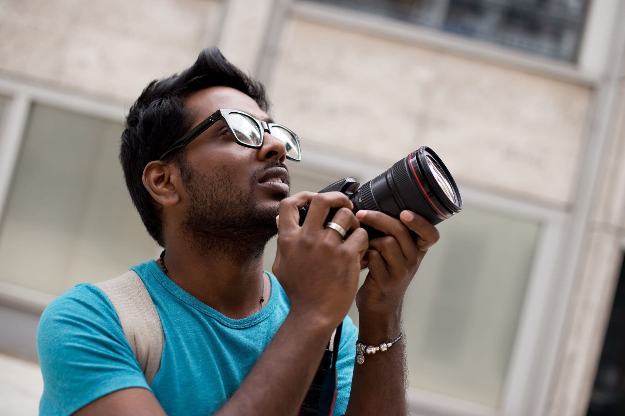 Summit Shah looking upward while holding a DSLR camera on a city street
